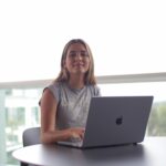 A young woman sits outdoors with a laptop, focused on online learning.